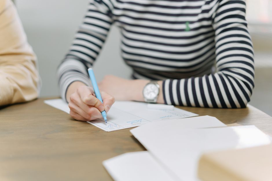 Adult writing with colored pen on documents, emphasizing strategic planning.