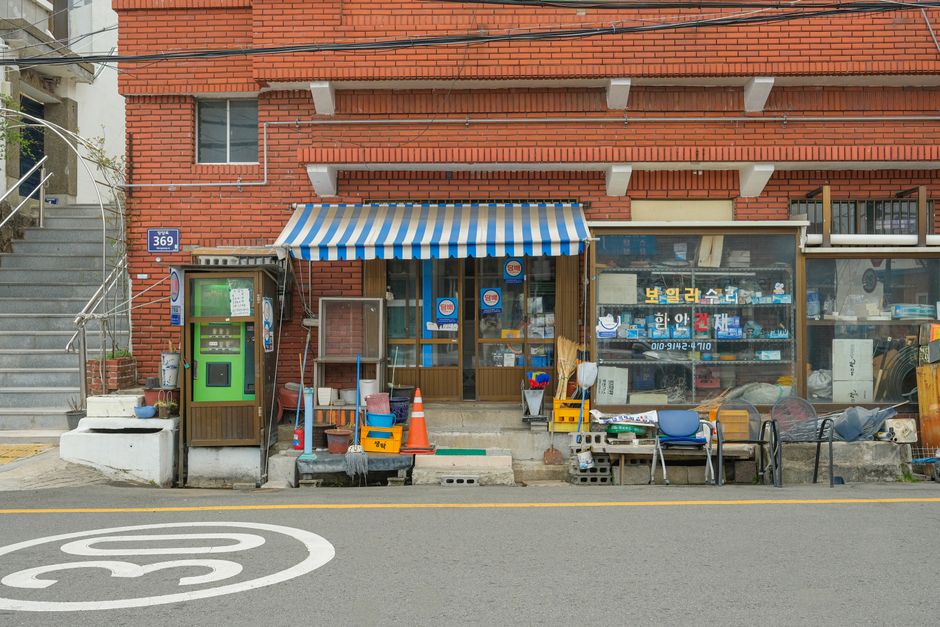 A quaint urban storefront with a retro feel, featuring a striped awning and eclectic store displays.